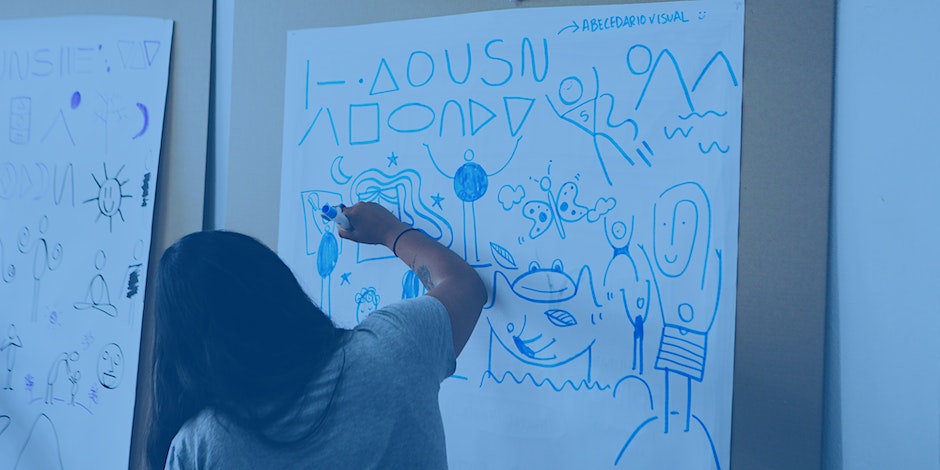 Woman facing away, drawing with a marker on a large sheet of paper